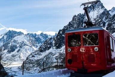 Red alpine train surrounded by snow-covered mountains